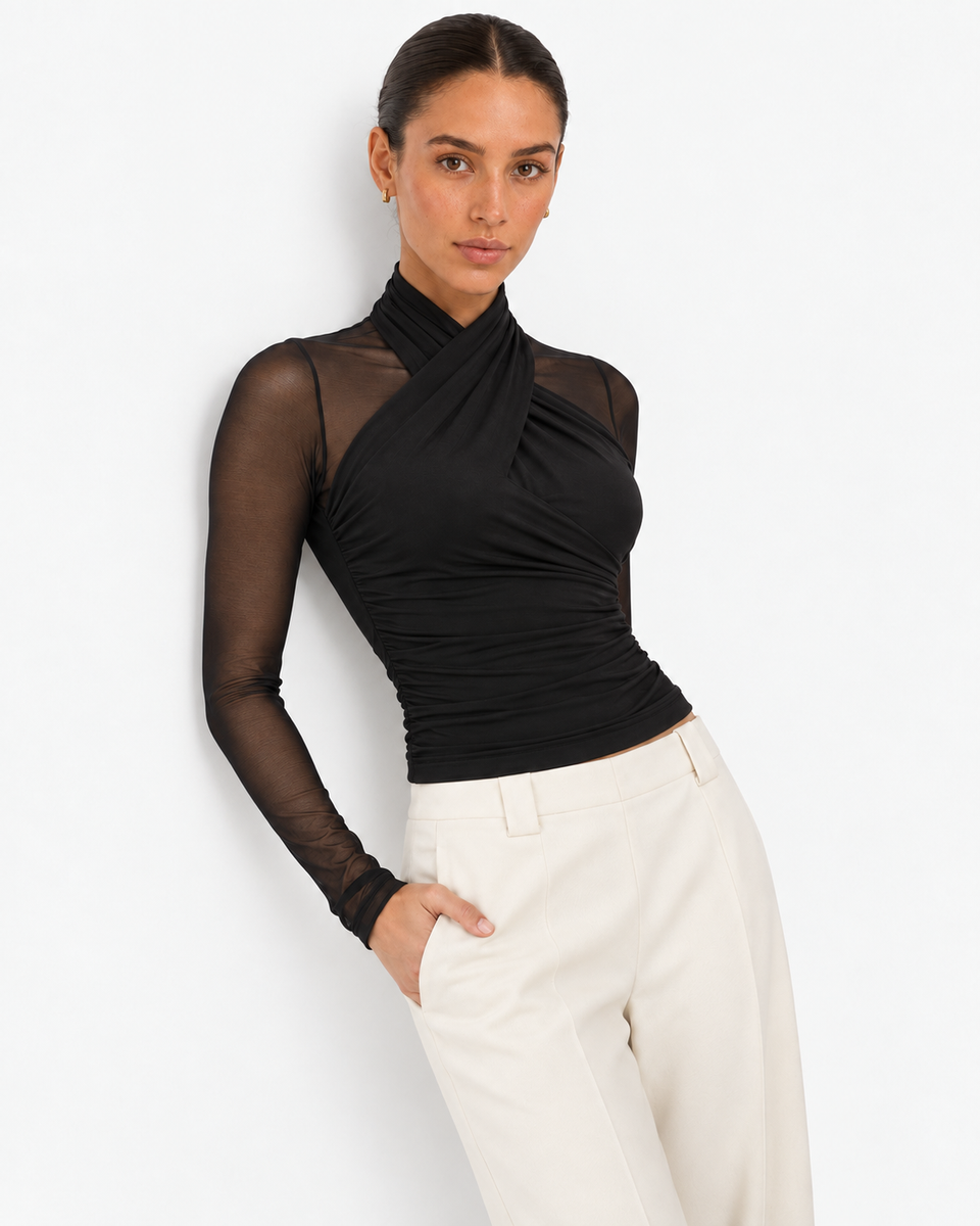Woman wearing the Aurore black draped mesh long sleeve top with ivory trousers, front view