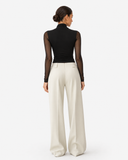 Back view of the Aurore black draped mesh long sleeve top styled with ivory trousers