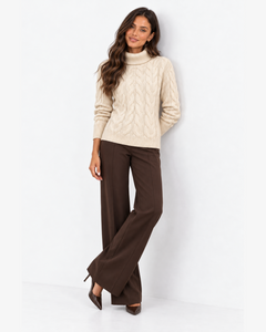 Harriet Apricot cable-knit roll-neck jumper, front styling with crossed legs and brown wide-leg trousers