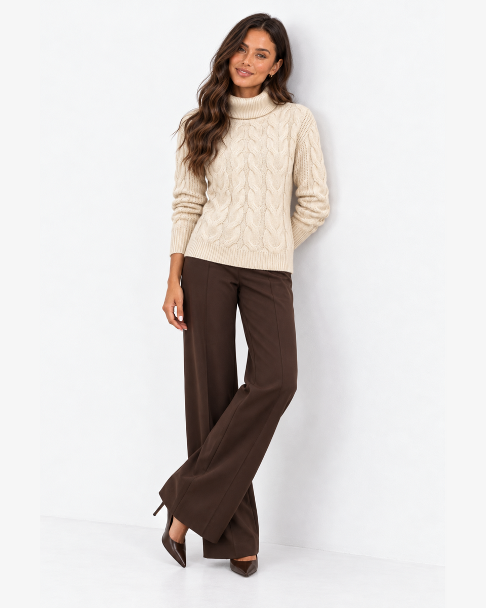 Harriet Apricot cable-knit roll-neck jumper, front styling with crossed legs and brown wide-leg trousers