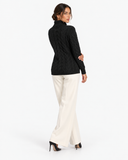Harriet Black cable-knit roll-neck jumper, back view with cream wide-leg trousers