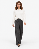 Front view of the white knit sweater tucked into charcoal trousers.