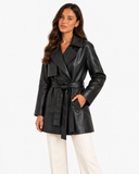Front view of Maren black belted faux leather trench coat styled with cream trousers