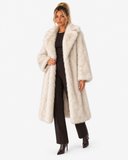 Full-length three-quarter view of the Claudine cream faux-fur coat, styled with black trousers.