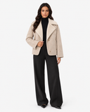 Full-length model view of the ivory Eveline teddy-lined suede-look jacket styled with black wide-leg trousers