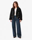 Full-length front view of the Vespera black suede-effect biker jacket styled with wide-leg jeans