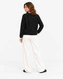 Three-quarter back view of the black long-sleeve knit sweater.