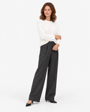 White round-neck knit sweater shown in a standing three-quarter pose with charcoal trousers.