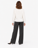 Back view of the white long-sleeve knit sweater with charcoal trousers.