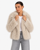 Closer view of the textured Beige Apricot faux-fur jacket with hands holding the front edges