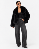 Full-length styling view of the Solenne black faux-fur jacket with grey jeans