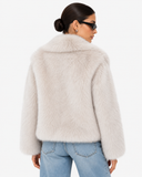 Back view of the Solenne ivory faux-fur jacket showing the hem and sleeve shape