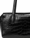 Close-up of the black crocodile-pattern finish, side panel and stitched handle attachment.