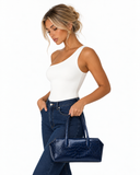 Woman holding a dark blue crocodile-pattern tote bag by its handles against a white background.