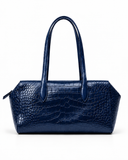 Front view of a dark blue crocodile-pattern tote bag with twin handles against a white background.