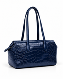 Three-quarter view of a dark blue crocodile-pattern tote bag showing its structured sides and twin handles.