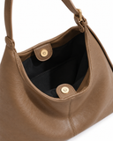Close-up of the khaki faux leather shoulder bag opening with gold-tone magnetic fasteners and black lining.